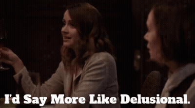 Two Women Are Sitting At A Table With The Words I 'D Say More Like Delusional GIF