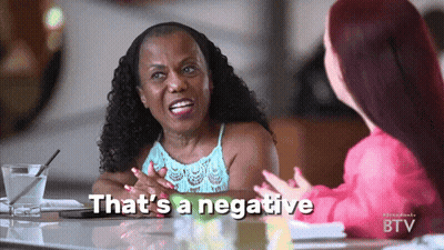 Two Women Are Sitting At A Table With The Words That 'S A Negative Written On The Screen GIF