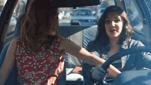 Two Women Are Sitting In A Car And One Is Wearing A Red Floral Dress GIF