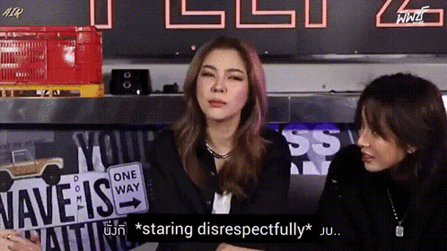 Two Women Are Sitting In Front Of A Sign That Says " Wave Is " GIF