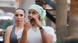Two Women Are Sitting Next To Each Other And One Of Them Is Wearing A Bandana On Her Head . GIF