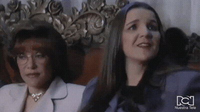 Two Women Are Sitting Next To Each Other In A Chair In A Room . GIF