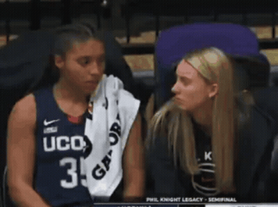 Two Women Are Sitting Next To Each Other In A Stadium . One Of The Women Is Wearing A Ucd Jersey . GIF