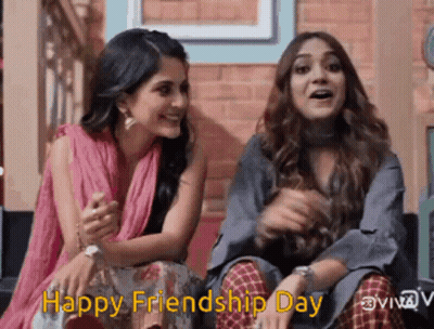 Two Women Are Sitting Next To Each Other In Front Of A Brick Wall And Smiling . GIF
