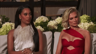 Two Women Are Sitting Next To Each Other On A Couch And One Is Wearing A Red Dress GIF