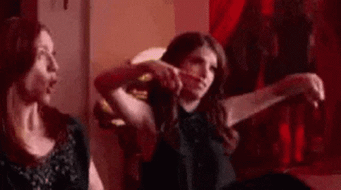 Two Women Are Sitting Next To Each Other On A Couch In A Room . GIF