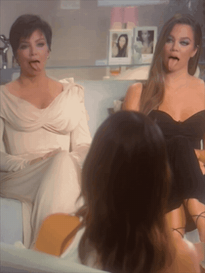Two Women Are Sitting On A Couch And One Is Sticking Her Tongue Out GIF