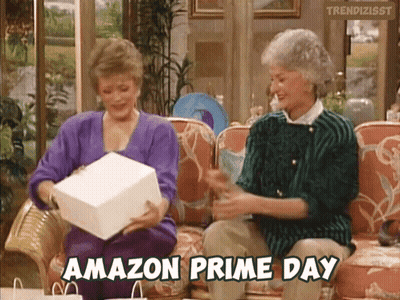 Two Women Are Sitting On A Couch And One Of Them Is Holding An Amazon Prime Day Gift GIF