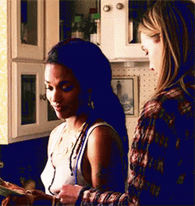 Two Women Are Standing In A Kitchen Looking At A Piece Of Paper . GIF