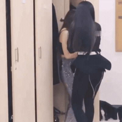 Two Women Are Standing In A Locker Room . GIF