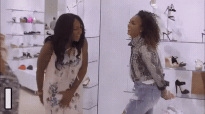 Two Women Are Standing In A Shoe Store Looking At Each Other . GIF