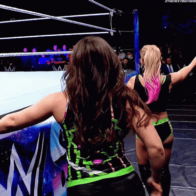Two Women Are Standing In A Wrestling Ring With Their Arms Outstretched And The Words " The Next Thing " On The Bottom R GIF