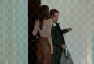 Two Women Are Standing In Front Of A Blue Door GIF