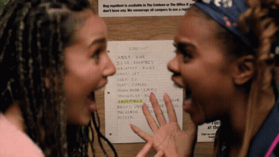 Two Women Are Standing In Front Of A Case List On A Wall GIF