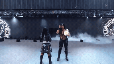 Two Women Are Standing In Front Of A Sign That Says " The Judge " GIF