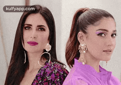 Two Women Are Standing Next To Each Other And Looking At The Camera . One Of The Women Is Wearing A Purple Shirt . GIF