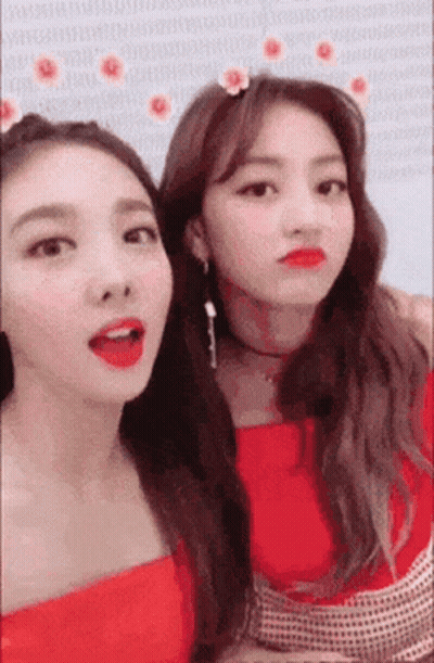 Two Women Are Standing Next To Each Other And Making Funny Faces . One Of The Women Is Wearing A Flower In Her Hair . GIF