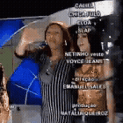 Two Women Are Standing Next To Each Other And One Is Drinking From A Glass . GIF
