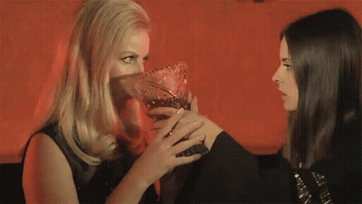 Two Women Are Standing Next To Each Other And One Is Holding A Vase GIF