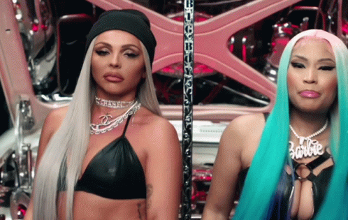 Two Women Are Standing Next To Each Other And One Of Them Has A Necklace That Says Barbie GIF