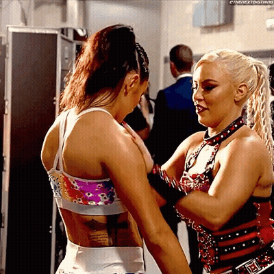 Two Women Are Standing Next To Each Other And One Of Them Has A Tattoo On Her Back . GIF