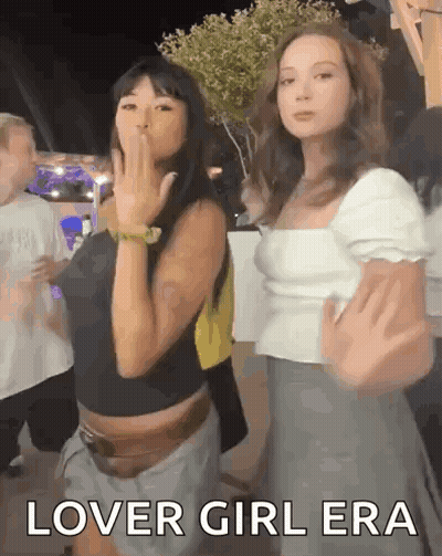 Two Women Are Standing Next To Each Other And One Of Them Is Blowing A Kiss While The Other Says Lover Girl Era GIF