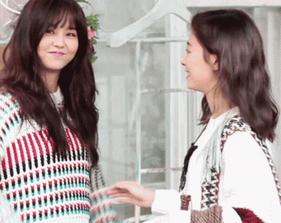 Two Women Are Standing Next To Each Other Holding Hands And Smiling GIF