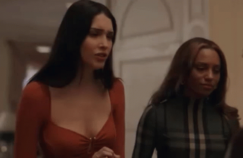 Two Women Are Standing Next To Each Other In A Hallway And Talking . GIF
