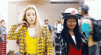 Two Women Are Standing Next To Each Other In A Hallway . One Of The Women Is Wearing A Yellow Plaid Shirt . GIF