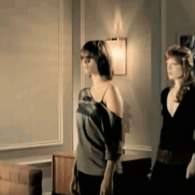 Two Women Are Standing Next To Each Other In A Living Room In Front Of A Wall . GIF