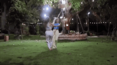 Two Women Are Standing Next To Each Other In A Park At Night . GIF