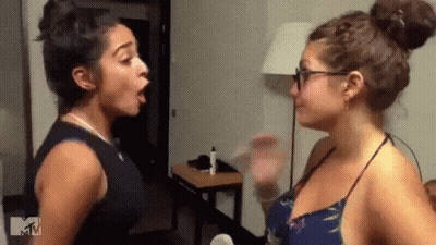 Two Women Are Standing Next To Each Other In A Room And Having A Fight . GIF