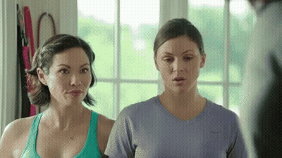 Two Women Are Standing Next To Each Other In A Room And Looking At Each Other . GIF