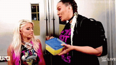 Two Women Are Standing Next To Each Other In A Room And One Is Holding A Lunch Box . GIF
