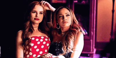 Two Women Are Standing Next To Each Other In A Room . One Of The Women Is Wearing A Red Polka Dot Dress . GIF