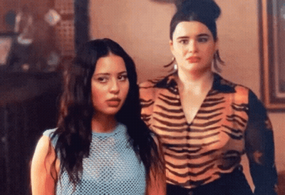 Two Women Are Standing Next To Each Other In A Room . One Of The Women Is Wearing A Tiger Print Shirt . GIF