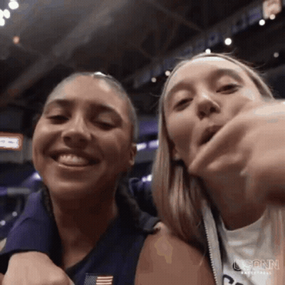 Two Women Are Standing Next To Each Other In A Stadium And Smiling At The Camera . GIF