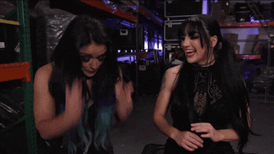 Two Women Are Standing Next To Each Other In A Warehouse And One Of Them Has Blue Hair GIF