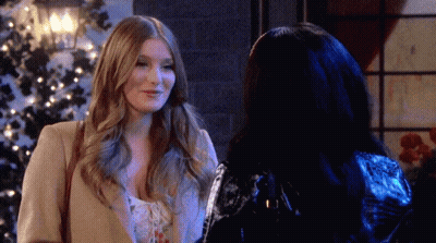 Two Women Are Standing Next To Each Other In Front Of A Christmas Tree And Smiling GIF