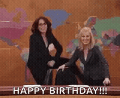 Two Women Are Standing Next To Each Other In Front Of A Desk . GIF