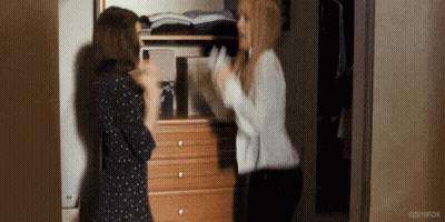 Two Women Are Standing Next To Each Other In Front Of A Dresser In A Room . GIF