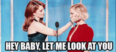 Two Women Are Standing Next To Each Other In Front Of A Microphone And One Of Them Is Touching The Face Of The Other . GIF