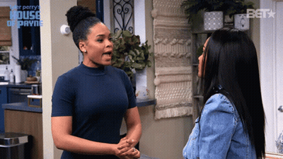 Two Women Are Standing Next To Each Other In Front Of A Sign That Says ' House Of Payne ' On It GIF