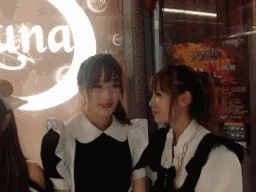 Two Women Are Standing Next To Each Other In Front Of A Sign That Says Una GIF