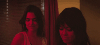 Two Women Are Standing Next To Each Other In Front Of A Window With Blinds . GIF