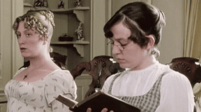 Two Women Are Standing Next To Each Other One Reading A Book GIF