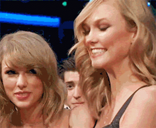 Two Women Are Standing Next To Each Other Smiling And Looking At The Camera GIF