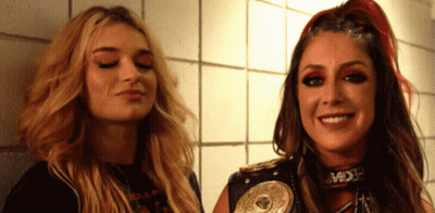 Two Women Are Standing Next To Each Other With One Wearing A Belt That Says ' Mdx ' On It GIF