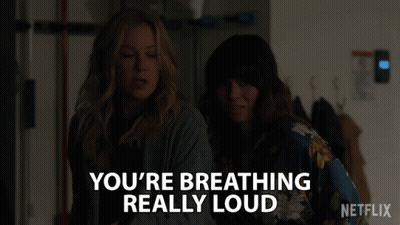 Two Women Are Standing Next To Each Other With The Words " You 'Re Breathing Really Loud " GIF