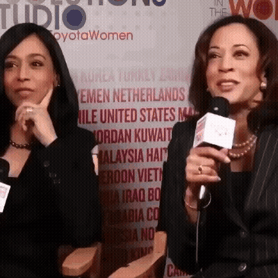 Two Women Are Talking Into Microphones In Front Of A Wall That Says " In The Wo " GIF